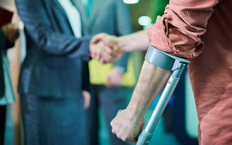 Person with crutches shaking hands with another person after a personal injury.